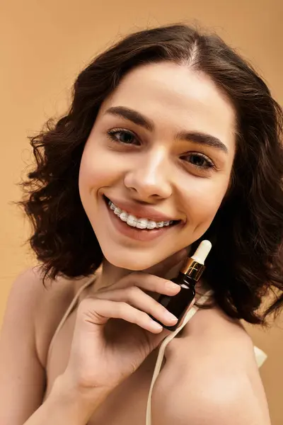 A young woman with braces confidently showcases her skincare routine in a studio. — Stock Photo