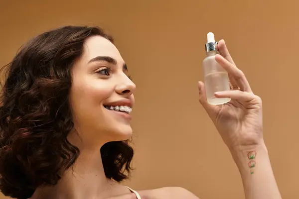 A young woman with braces happily demonstrates her skincare routine in a studio setting. — Stock Photo