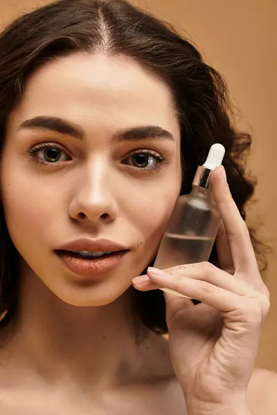 Pretty young woman with braces demonstrates her skin care routine while posing with a serum. — Stock Photo