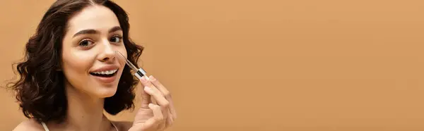 In a bright studio, a young woman proudly showcases her beauty skincare routine while smiling, banner — Stock Photo