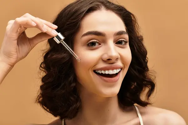 A young woman with braces joyfully demonstrates her skincare routine in a studio atmosphere. — Stock Photo