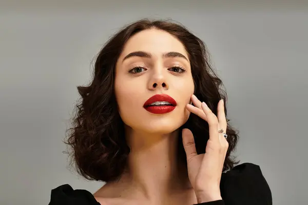 A beautiful young woman showcases her radiant red lips and braces while gently touching her face. — Stock Photo