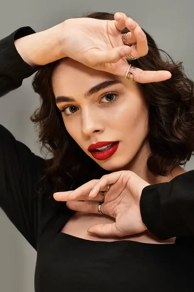 A beautiful young woman displays stunning red lips against a grey backdrop. — Stock Photo