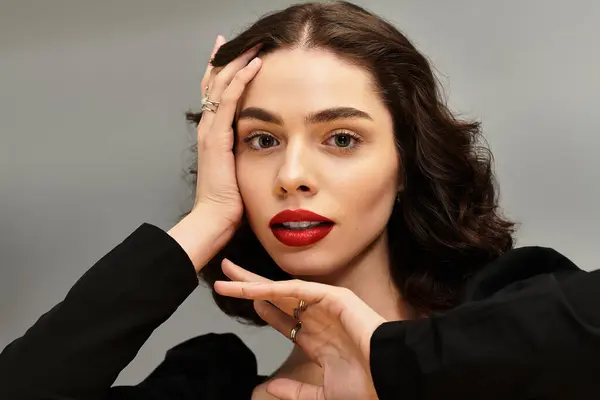 A young woman poses gracefully against a grey backdrop, showing off her red lips and braces. — Stock Photo
