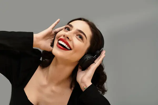 Young woman with braces and striking red lips smiles joyfully against a grey background. — Stock Photo