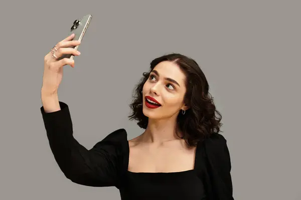 A beautiful young woman with braces and striking red lips captures a playful selfie. — Stock Photo
