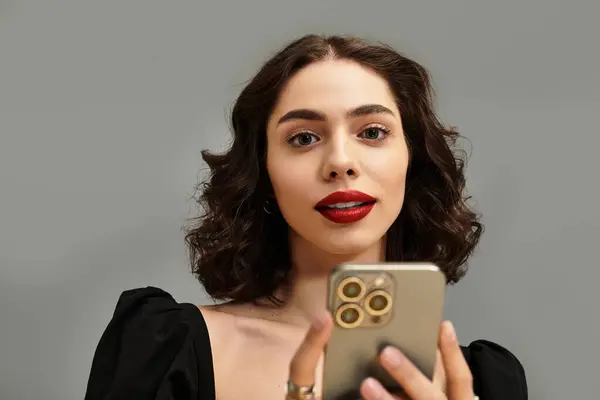 A charming young woman with curly hair and red lips engages with her smartphone. — Stock Photo