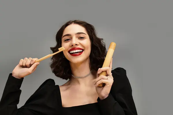 Uma jovem mulher vibrante com lábios e aparelhos vermelhos sorri, segurando uma escova de dentes e uma ferramenta dentária. — Fotografia de Stock