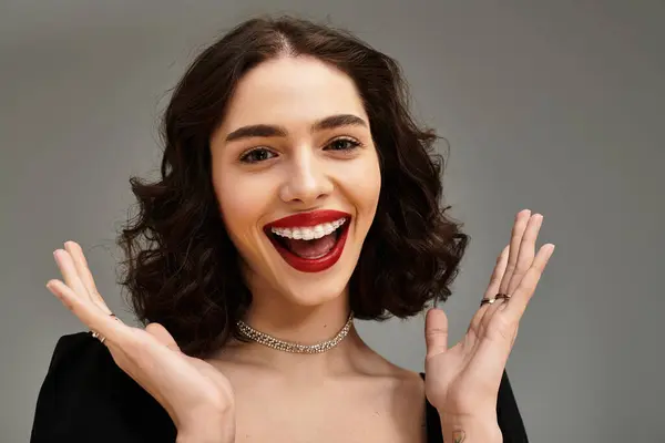 A cheerful young woman with braces and red lips smiles brightly against a grey backdrop. — Stock Photo