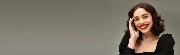 A young woman with braces smiles confidently, showcasing her red lips against a grey background, banner — Stock Photo