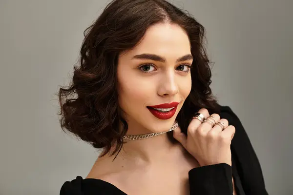 A young woman with vibrant red lips exudes confidence against a grey backdrop. — Stock Photo