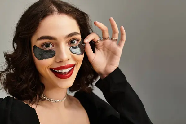 Una giovane donna sorride giocosamente, mostrando le sue bretelle e le sue labbra rosse audaci con sotto le bretelle — Foto stock