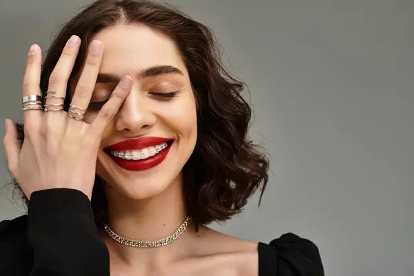 Una bella giovane donna con l'apparecchio e le labbra rosse sorprendenti sorride giocosamente, evidenziando la sua bellezza. — Foto stock