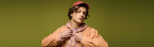 A young man poses confidently in trendy attire, expressing youthful energy in a vivid setting. — Stock Photo