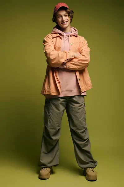 Stylish young man poses confidently in trendy attire against a lively green background. — Stock Photo
