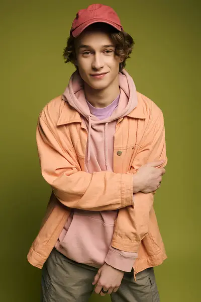 A young man poses confidently in stylish clothes against a vibrant green background. — Stock Photo