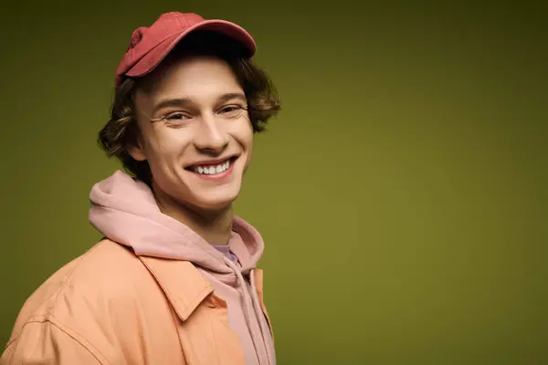 A stylish young man in casual attire exudes confidence and warmth against a bold green backdrop. — Stock Photo