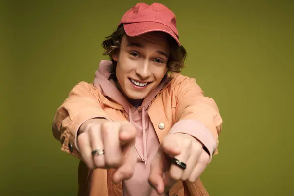 In a lively setting, a young man displays his trendy outfit and enthusiasm with a joyful gesture. — Stock Photo