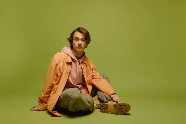 A stylish young man confidently poses on a green background, showcasing modern fashion. — Stock Photo
