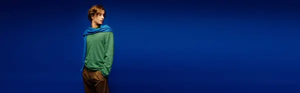 Selbstbewusster junger Mann präsentiert trendiges Outfit mit stylischem Schal in auffallend blauem Rahmen. — Stockfoto