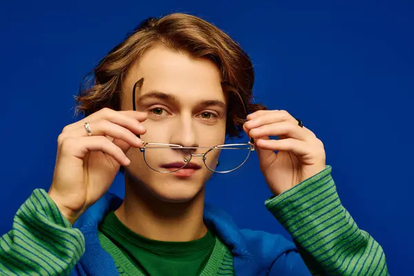 A stylish young man adjusts his glasses, embodying modern youth culture and confidence. — Stock Photo