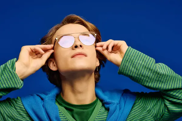 Charming young man in stylish attire adjusts his sunglasses, exuding confidence and trendiness. — Stock Photo