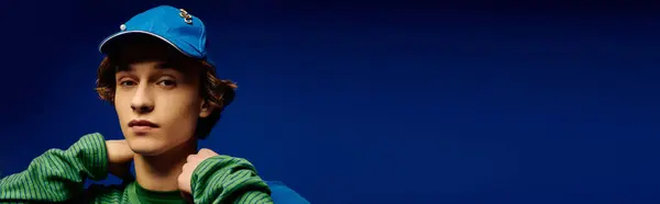 Fashion forward young man showcases trendy style with distinctive cap and bold green sweater. — Stock Photo