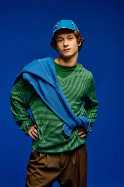 Un jeune homme modélise en toute confiance une tenue tendance sur un fond bleu vif. — Stock Photo