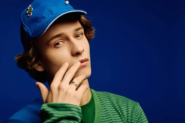 In a striking blue backdrop, a young man displays trendy attire and fashionable confidence. — Stock Photo