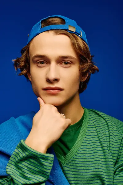 A young man poses thoughtfully, wearing stylish attire that reflects current youth culture trends. — Stock Photo