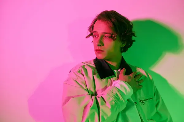 Young man captures attention with fashionable attire and striking pose in colorful neon light. — Stock Photo