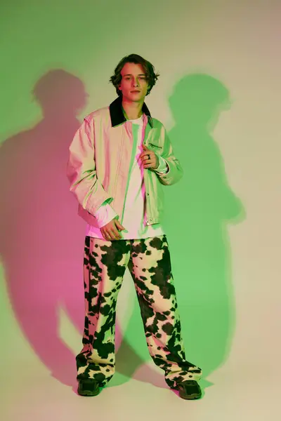 Stylish young man poses confidently in trendy clothes against a vibrant backdrop. — Stock Photo