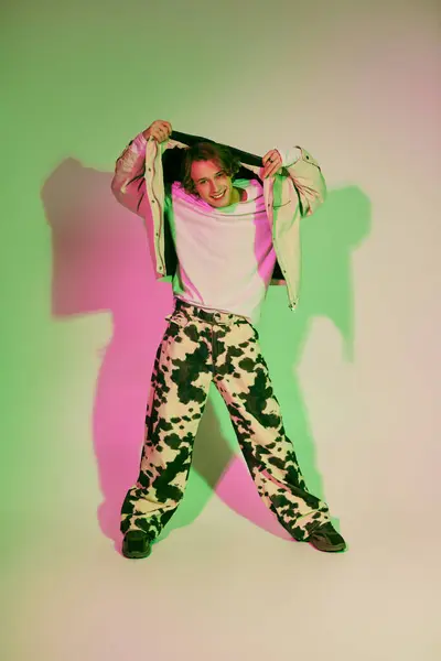 A stylish young man displays modern fashion sense in an artistic studio with colorful lighting. — Stock Photo