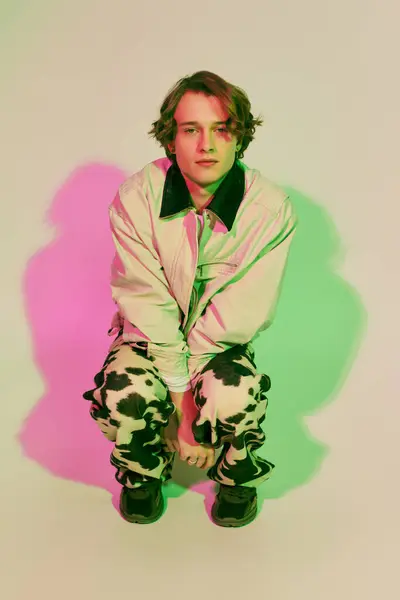 A young man poses confidently in a trendy outfit that blends modern style and bold colors. — Stock Photo