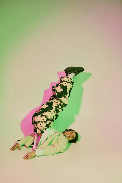 A stylish young man strikes a playful pose against a vibrant, colorful backdrop. — Stock Photo