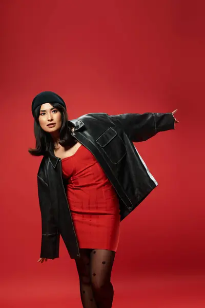 A stylish young Asian woman confidently poses in a red dress and oversized jacket. — Stock Photo