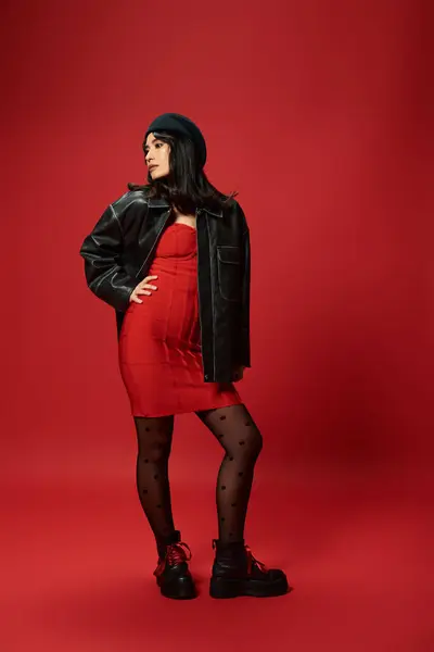 A young Asian woman poses confidently in a red dress with a stylish jacket. — Stock Photo