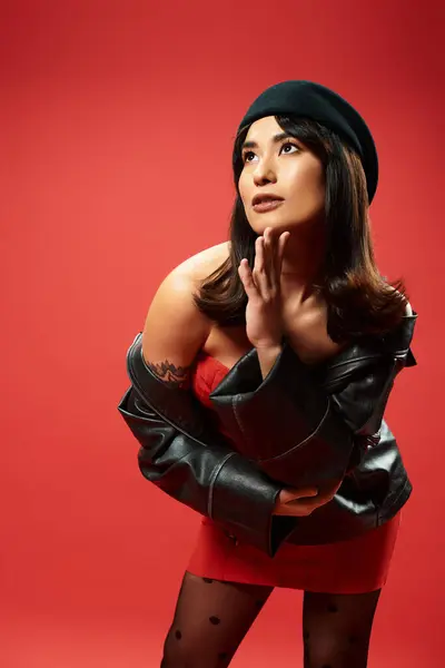Dynamic young woman in stylish attire exudes confidence against a vibrant red background — Stock Photo