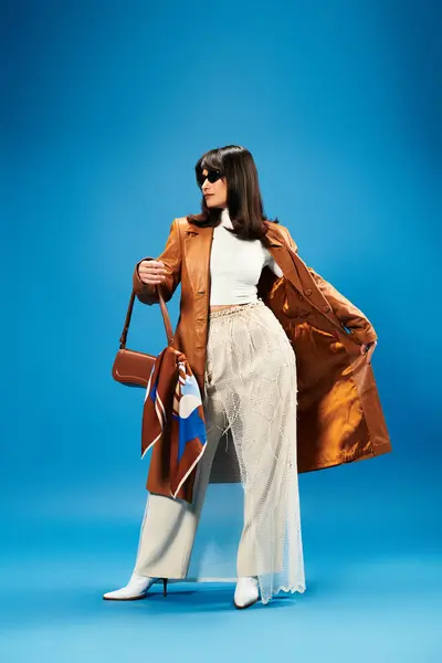 Fashionable young asian woman poses confidently against a bright blue backdrop, exuding style. — Stock Photo