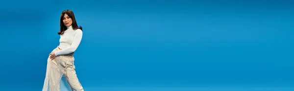 Fashionable young woman poses confidently against a bold blue backdrop, exuding charisma. — Stock Photo