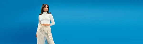 Giovane donna asiatica con fiducia modelli di tendenza abbigliamento contro un vibrante sfondo blu. — Foto stock