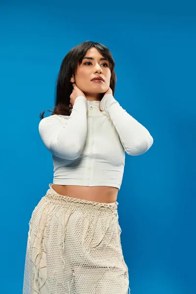 A young Asian woman poses confidently in trendy clothes against a striking blue background. — Stock Photo