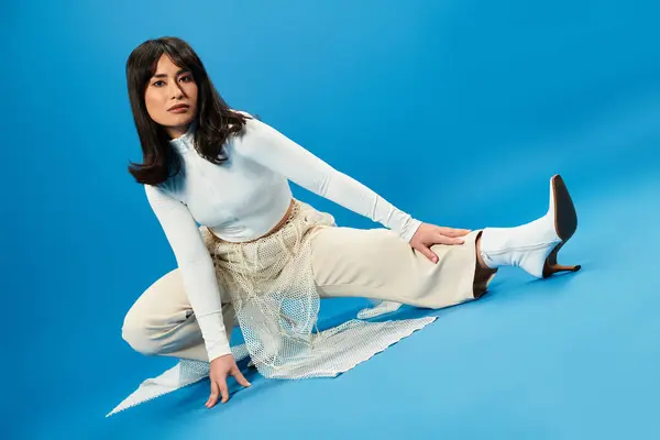 Modèle en tenue élégante pose avec confiance sur un fond bleu audacieux. — Photo de stock