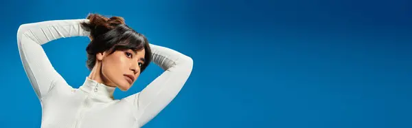 A young Asian woman poses confidently in a striking blue setting, showcasing her trendy style. — Stock Photo