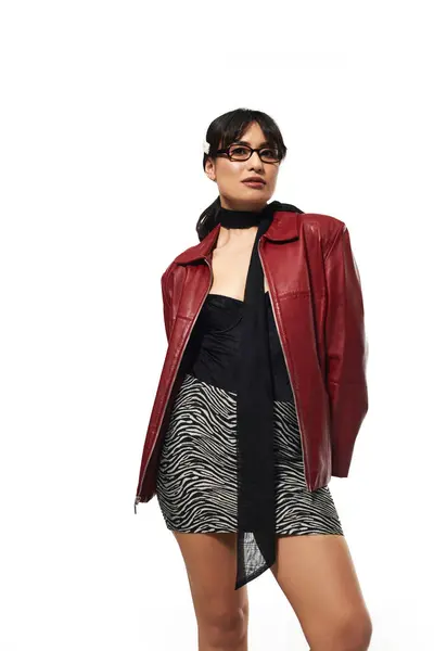 Confident young woman in a chic outfit stands against a minimal backdrop. — Stock Photo