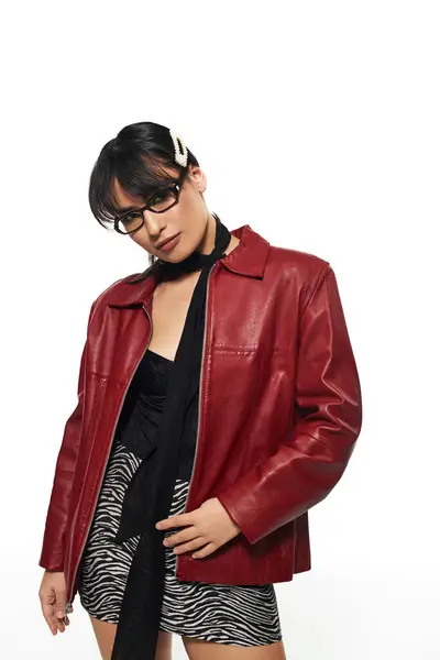 A stylish young Asian woman confidently shows off her trendy outfit in a minimal backdrop. — Stock Photo