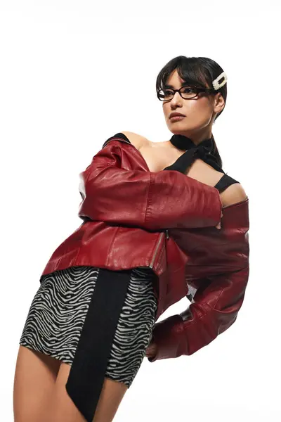 Trendy Asian woman poses confidently in a leather jacket against a creative urban backdrop. — Stock Photo