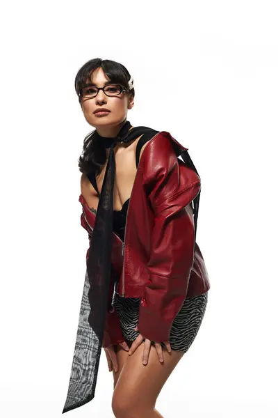 A stylish Asian woman poses confidently in eye catching red outerwear, blending elegance and trend. — Stock Photo