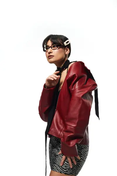Jeune femme à la mode affiche son style unique portant une veste rouge vibrante dans un studio. — Photo de stock