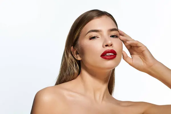 A graceful young woman showcases her beauty with bold red lips against a bright backdrop. — Stock Photo